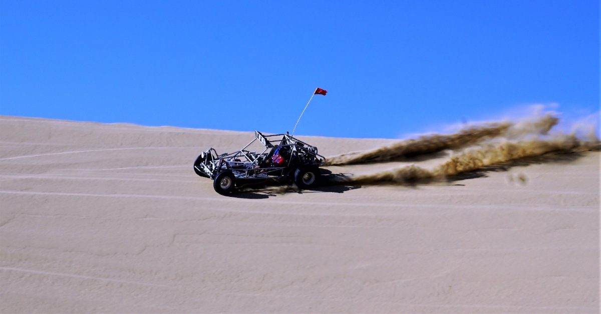 Person riding a side by side on sand dunes
